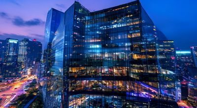 亚洲某国际金融中心大楼外景，51大事件经济大事件专题，夜晚霓虹灯光映照玻璃幕墙，城市经济繁荣感
